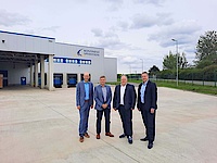 Vier Männer in Anzügen stehen vor der Kontinent Spedition GmbH und schauen in die Kamera.
