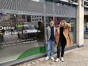 Ein Mann und eine Frau stehen vor dem Schaufenster des neuen StadtLab Jenas in der Löbderstraße 6.