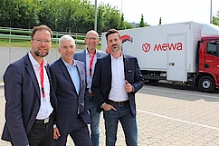 Vier Personen posieren vor einem Firmen-LKW